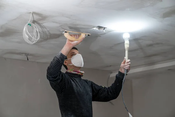 sanding a plasterboard ceiling in a new building with a trowel. High quality photo