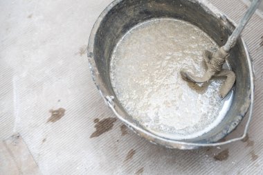 Elle çimento karıştırma, elektrikli mikser yardımıyla, inşaat alanında bir kovada çimento. Yüksek kalite fotoğraf