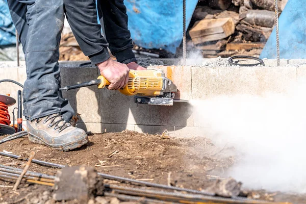 Stock image cutting concrete bricks with an electric grinder. 