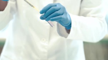 Bilimsel bir laboratuvarda araştırma yapmak için kimyasal numuneleri mataralara boşaltıyor.. 