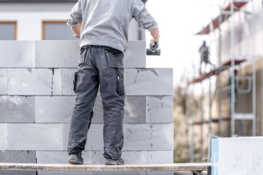 Duvarcı, beton tuğlalardan ve bloklardan bir bina inşa eder. Yüksek kalite fotoğraf