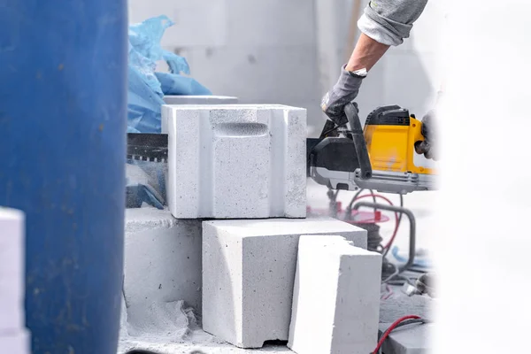 cutting concrete blocks with a saw during the construction of a building wall.