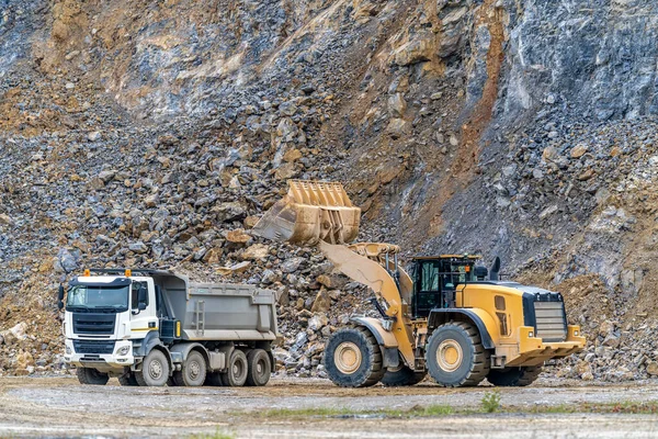 stock image an excavator is loading a truck with stone at a quarry. High quality photo