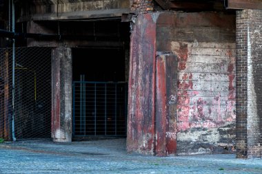 Soyulmuş boya ve grafiti ile eski sanayi binası şehir manzarasında çürüme gösteriyor, çatlamış beton ve yıpranmış çelik cesur bir görünüm veriyor.