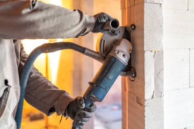 İnşaat işçisi dairesel testere ve vakum tozu çıkarma sistemiyle havalandırılmış beton blok duvarı keserek temiz ve güvenli bir çalışma ortamı sağlıyor.