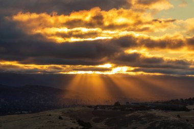 Sun setting and beaming through clouds at Santa Teresa County Park, Santa Clara County, California. clipart