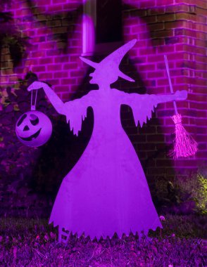 A Witch Decorating a Yard for Halloween.  clipart