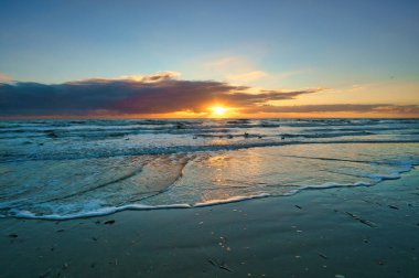 Danimarka sahilinde gün batımı. Ön planda mermiler var. Sahilde yürü. Deniz kenarındaki manzara fotoğrafı.