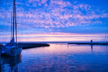 Sailing ship in the harbor of lake Vaettern at sunset. Lighthouse in the background. Landscape shot from Scandinavia clipart