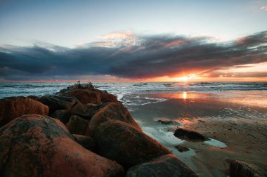 Danimarka sahilinde gün batımı. Stone Groyne ön planda. Sahilde kumda yürü. Deniz kenarındaki manzara fotoğrafı.