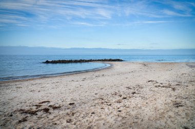 Danimarka sahilindeki kumsal. Koyda Stone Groyne, yürürken güneş ışığı. Deniz kenarındaki manzara fotoğrafı.