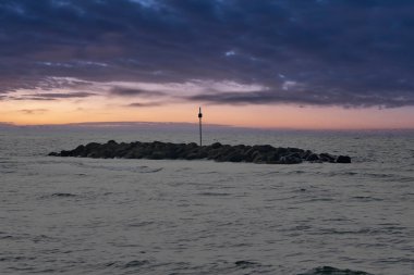 Stone Groynes, Danimarka kıyılarında dalgalar var. Akşamları gökyüzünde bulutlarla. Deniz kenarındaki manzara fotoğrafı.