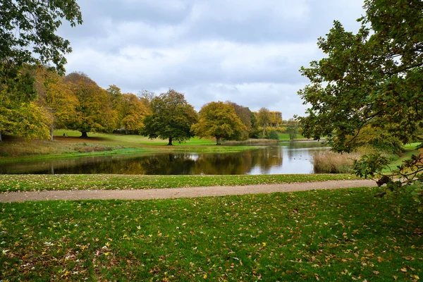 庭の牧草地や景観湖に強大な落葉樹と秋のフレデリックスボー城公園 葉のカラフルな色 デンマークを歩く — ストック写真
