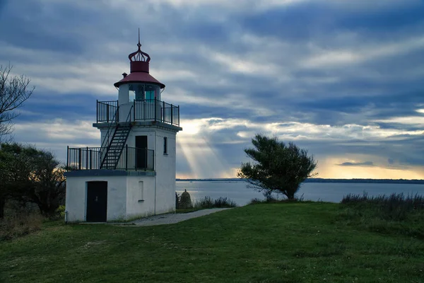 丹麦海岸亨茨特德的斯波茨堡灯塔 阳光透过云彩闪耀 有树木的草地 海景照片 — 图库照片