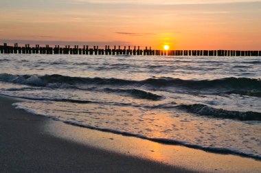 Sunset on the Baltic Sea. Sea, groyne strong colors. Vacation on the beach. Romantic mood on the coast. Landscape photo.