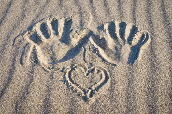 Hand print with heart in sand on beach. Corrugated sand. Still life on the seashore. Vacation memories from the coast