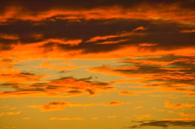 Background image with clouds in extreme colors of a sunset. The sky seems to burn. Photo from nature