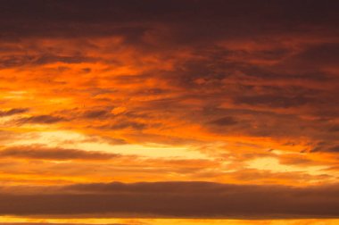 Background image with clouds in extreme colors of a sunset. The sky seems to burn. Photo from nature