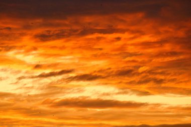 Background image with clouds in extreme colors of a sunset. The sky seems to burn. Photo from nature