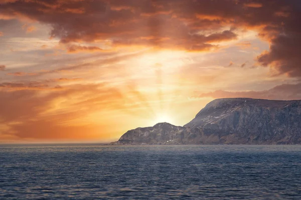 日落时从海上俯瞰挪威的西开普省 阳光照在岩石上 波浪在前景中 岩石在背景中 欧洲大陆的最西端 免版税图库图片