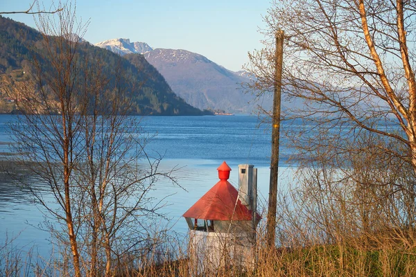 stock image Nordfjord in Norway. View of mountains covered with snow. In the foreground a small lighthouse. Wilderness in Scandinavia, in sunshine. Landscape photo from the north