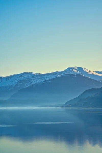 stock image View of Oppstrynsvatnet lake in Norway in the morning hours. Snow covered mountains in the background. Calm water in mountain lake. Landscape shot from Scandinavia.