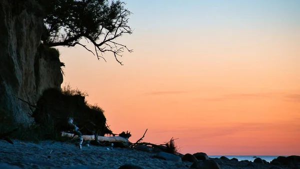 stock image Steep coast on the island of Poel at sunset with a view of the pastel sky over rocks lying in the Baltic Sea. Landscape shot from the coast