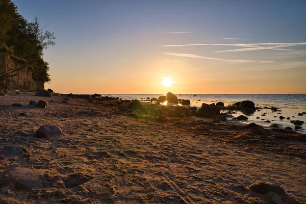 stock image Sunset, stone beach with small and large rocks in front of the illuminated sea. Light waves. Poel island on the Baltic Sea. Nature photo from the coast