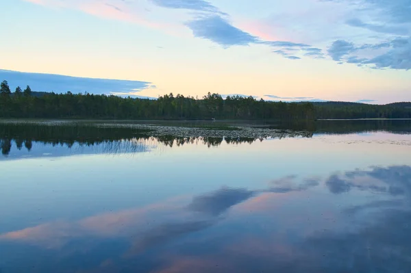 Calm lake in Sweden at blue hour sunset. Clouds reflected in the water. Swimming fun on vacation with recreation in Scandinavia
