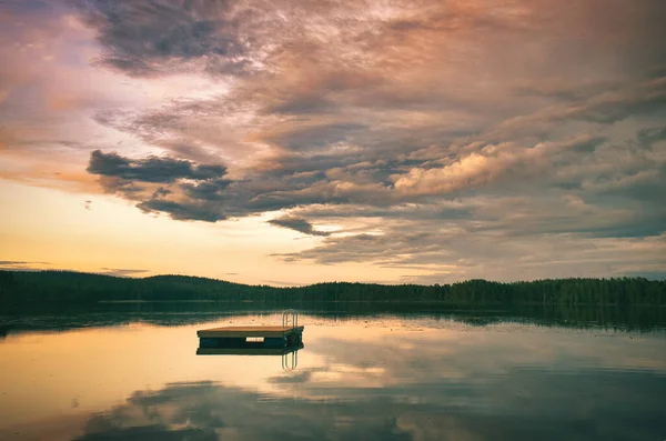 Swimming island in Sweden on a lake at sunset. Clouds reflected in the water. Swimming fun on vacation with recreation in Scandinavia