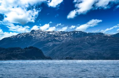 Ufukta dağları olan fiyort. Norveç 'te su güneşte parlar. Kuzeyden manzara fotoğrafı.