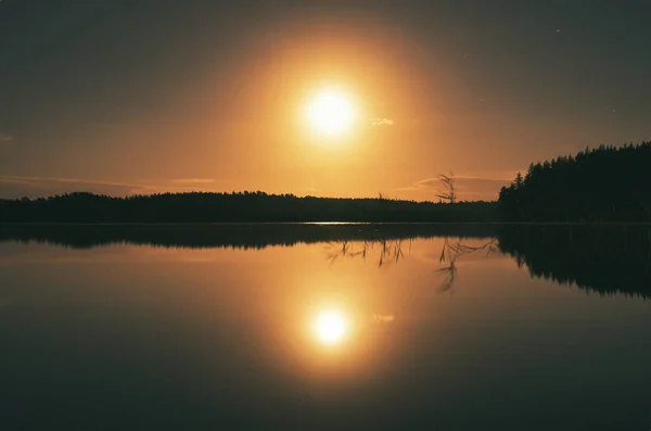 Sunset on a lake in Sweden. The moonlight is reflected in the calm water. Nature photo from Scandinavia