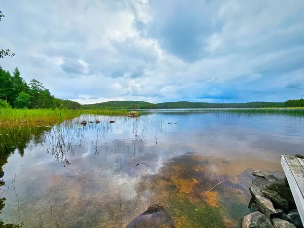 View of a lake in Smaland in Sweden. Blue water with light waves and reeds. Blue sky with veil clouds. Summer in nature in Scandinavia. Landscape photo