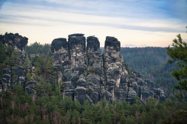 Basteibridge 'deki engebeli kayalar. Ağaçların ve dağların üzerinden geniş görüş. Almanya 'daki Ulusal Park