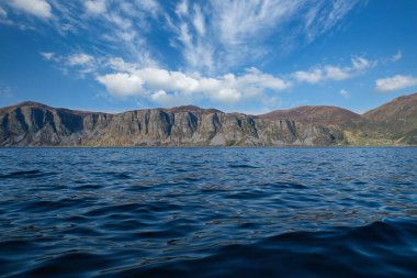 Norveç fiyort manzarası. Dağların engebeli bitki örtüsü manzarası. Ön planda kristal berrak su var. İskandinavya 'dan manzara