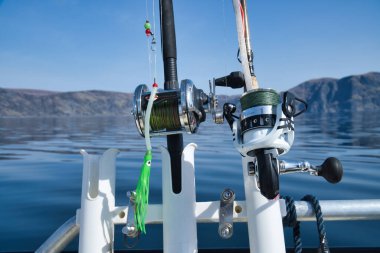 Olta kamışı ile balıkçı teknesi ve Norveç fiyortlarında dağlarda makaralar. İskandinavya 'da kristal berrak su