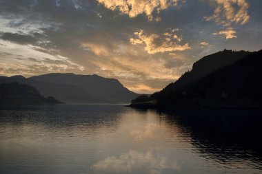 Günbatımında açık deniz manzaralı Norveç fiyort manzarası. İskandinavya 'nın doğasında su ve dağlar