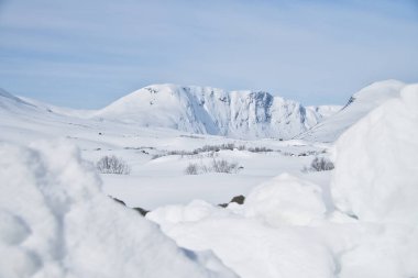Karda Norveç yüksek dağları. Dağlar karla kaplı. Uzak kuzeydeki İskandinav manzarası