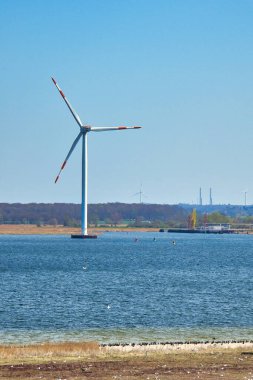 Açık denizde, sahilde rüzgar türbini var. Geleceğin yeşil enerjisi. Yenilenebilir enerji kaynağı. İklim değişikliğiyle mücadelede. Yeşil elektrik