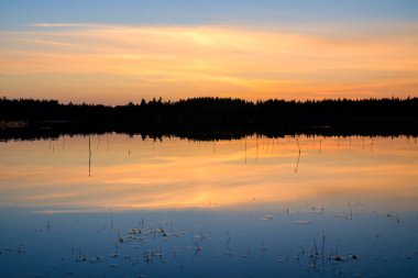 Smalland 'daki İsveç gölünde sıcak renklerle gün batımı. Romantik akşam atmosferi. İskandinav doğası