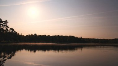 İsveç 'te göl, aynadan pürüzsüz su, romantik ışık ve kıyıda ağaçlar. İskandinav doğası