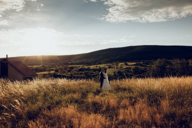 Gelin ve damat düğün çekimlerinde İsa 'nın heykeli önünde el ele tutuşuyorlar. Beyaz elbiseli güzel gelin ve şık damat.