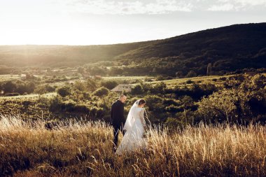 Gelin ve damat düğün çekimlerinde İsa 'nın heykeli önünde el ele tutuşuyorlar. Beyaz elbiseli güzel gelin ve şık damat.