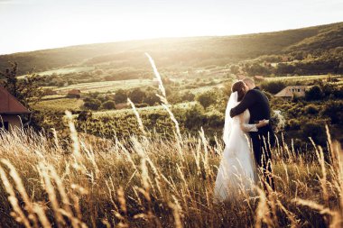 Gelin ve damat düğün çekimlerinde İsa 'nın heykeli önünde el ele tutuşuyorlar. Beyaz elbiseli güzel gelin ve şık damat.