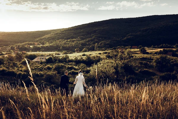 結婚式の写真撮影中にイエス キリスト像の前で手を握っている花嫁と新郎 白いドレスとスタイリッシュな新郎の美しい花嫁 — ストック写真