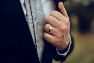 Ceketinde yüzük ve gömleği olan damat, zarif bir genç adam.