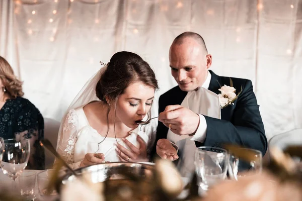 the bride and groom are fed soup during the wedding reception