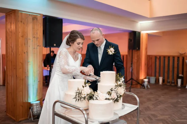 在婚宴上 新婚夫妇在一个装饰精美的空间里互相切蛋糕 结婚蛋糕 — 图库照片
