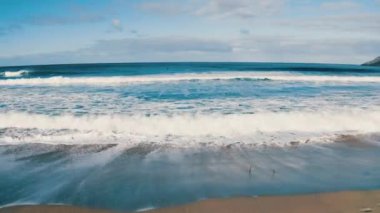 Dalgalar sahile doğru ilerliyor. Lofoten plaj dalgaları, Norveç dalgaları, Norveç denizi, Lofoten dağları, dalgalı deniz, Norveç plajı, Lofoten manzarası, 4K drone çekimi, plaj, Uttakleiv kıyısı, muazzam okyanus dalgaları.