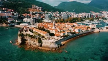 Areal shot over the Budva  adriatic coast, old town and the city. Picturesque view in Budva.4k drone shot of the coast, beatiful clear water.Summer adventures in the Montenegro.Architecture,buildings.